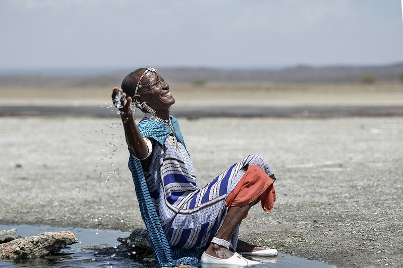 A Maasai woman is sprinkling her feet with hot spring water in Lake Magadi.